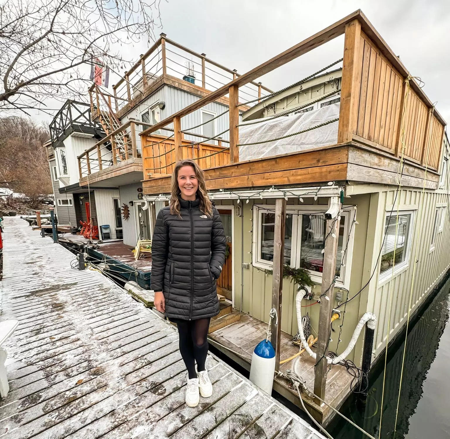A woman standing in front of a houseboat during winter.
