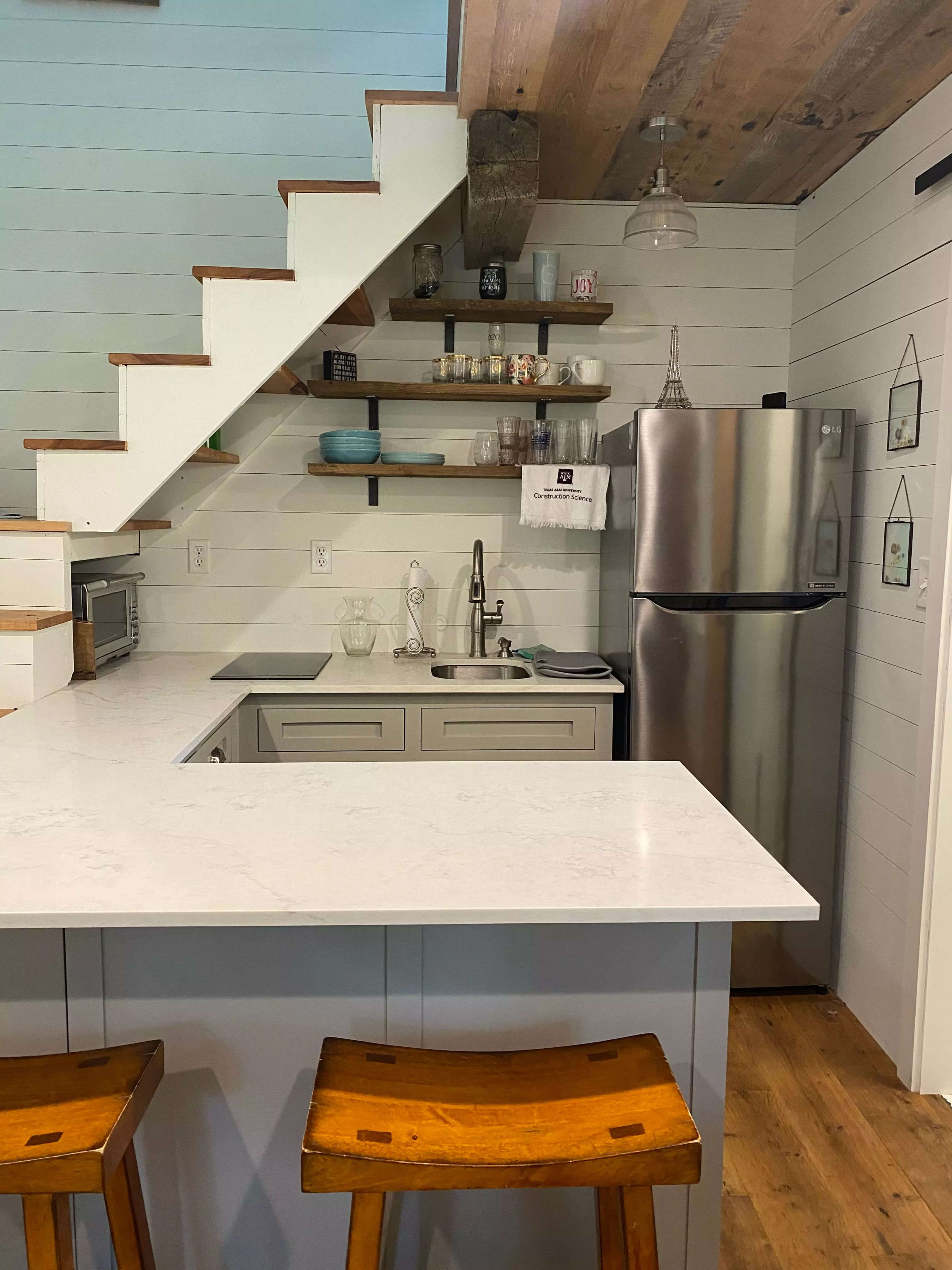 A tiny kitchen with a full-sized fridge and U-shaped countertop.