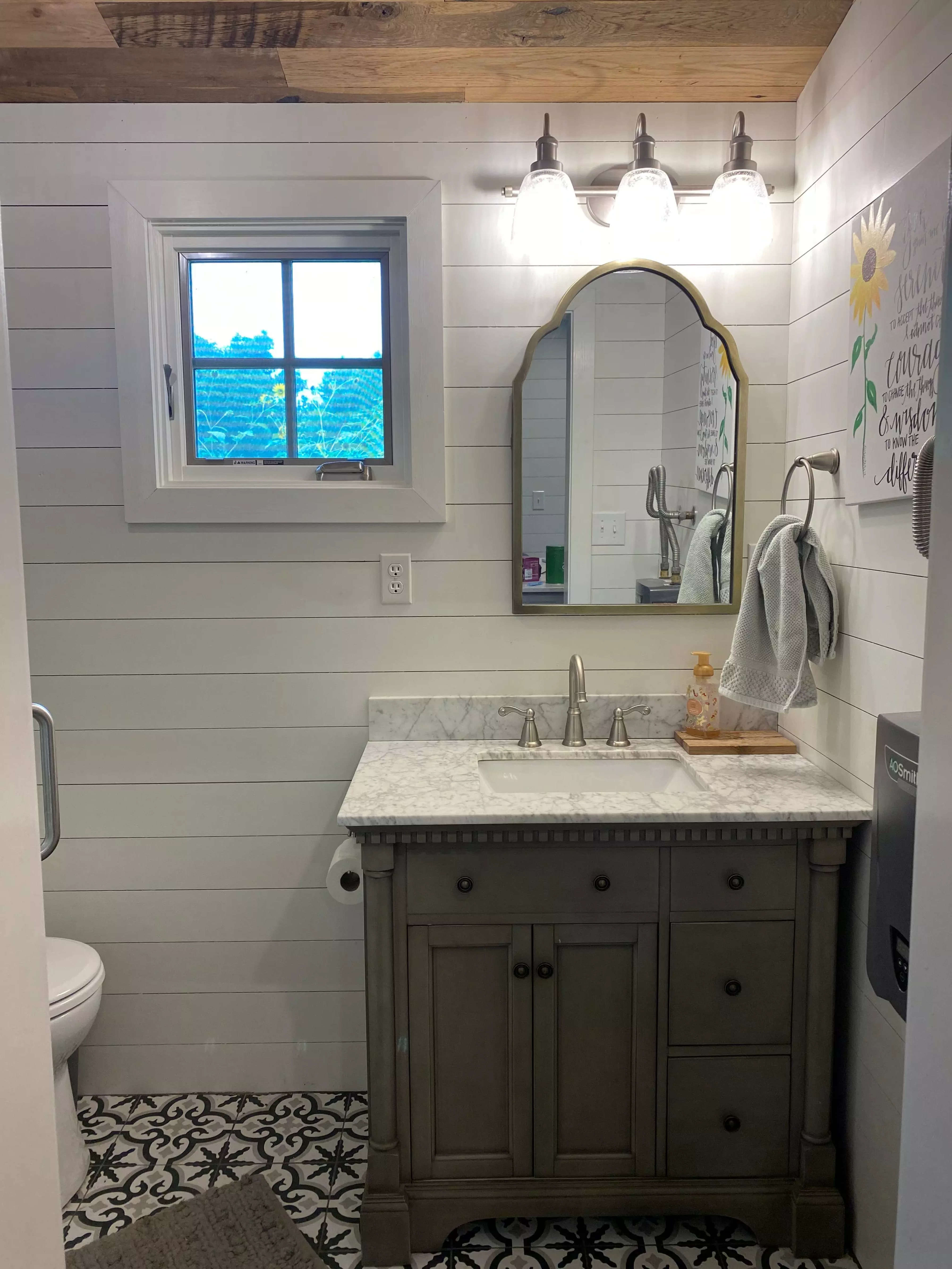 A tiny home bathroom sink and mirror with toilet and small shower.
