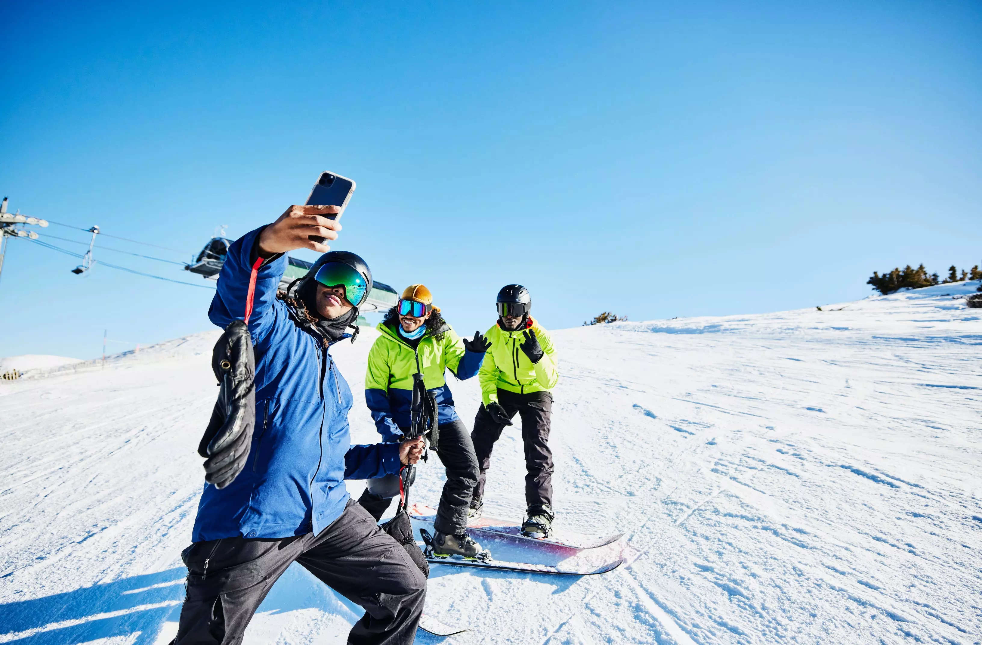 People taking a selfie while snowboarding on a mountain.