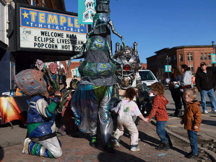 People dressed as alien creatures walk through the main square during the eclipse festival in Houlton.