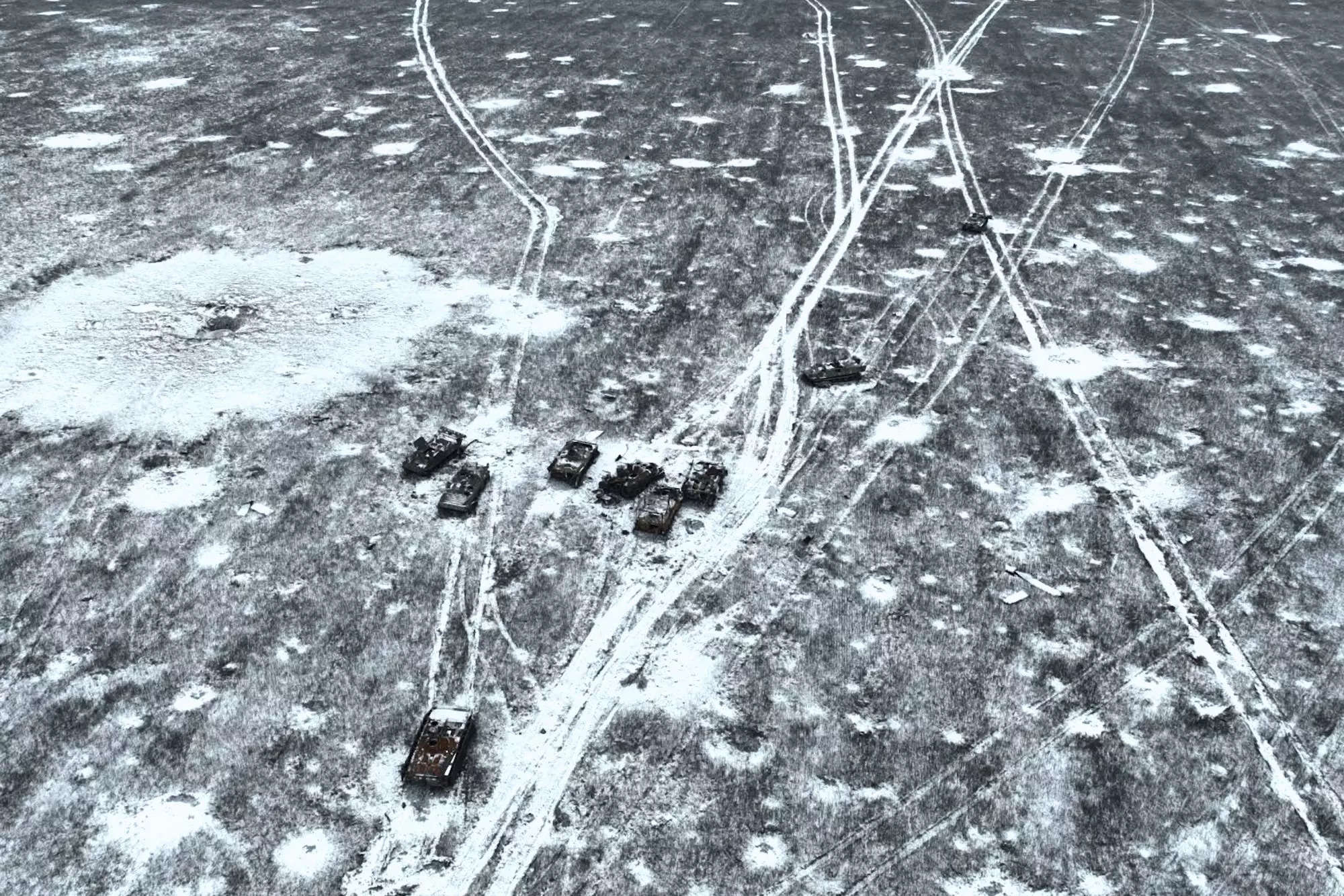 An aerial photo of a snowy field with traces of artillery and recently destroyed Russian heavy equipment