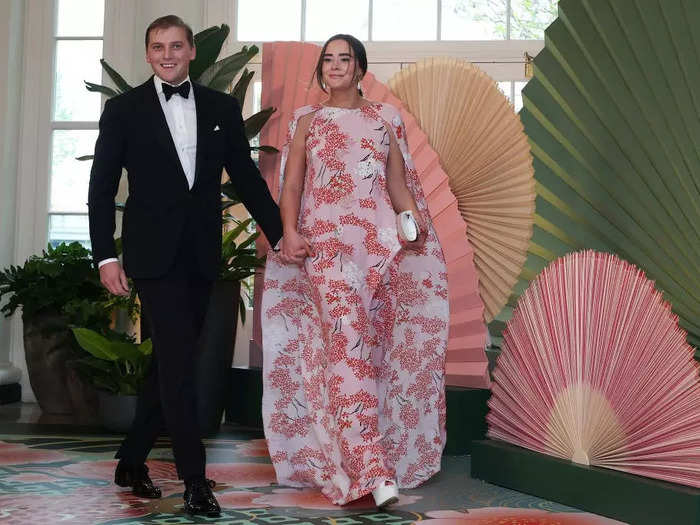 Naomi Biden wore a pink cape dress printed with cherry blossoms from Belgian designer Bernadette.