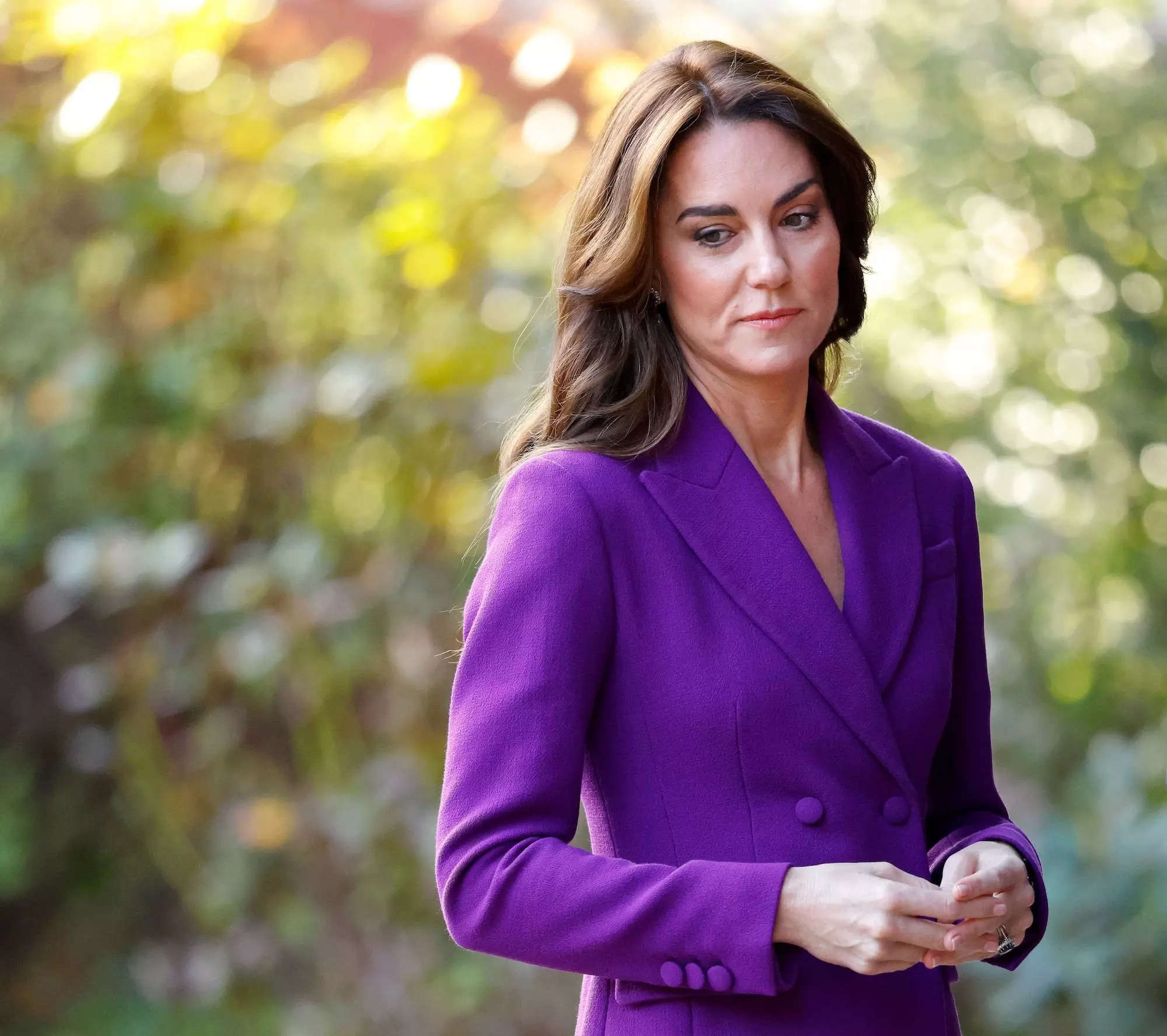 Kate Middleton looks down in a purple suit.