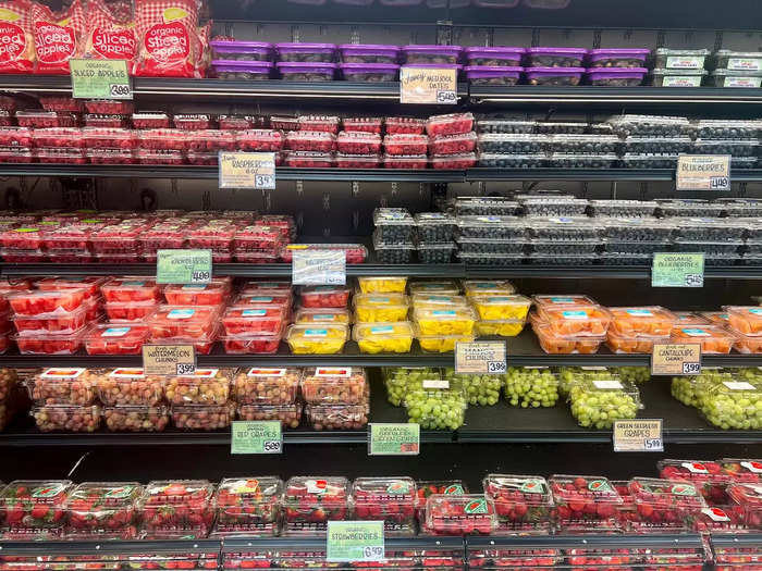 Sliced fruit, grapes, and strawberries filled in a different section of the refrigerator. 