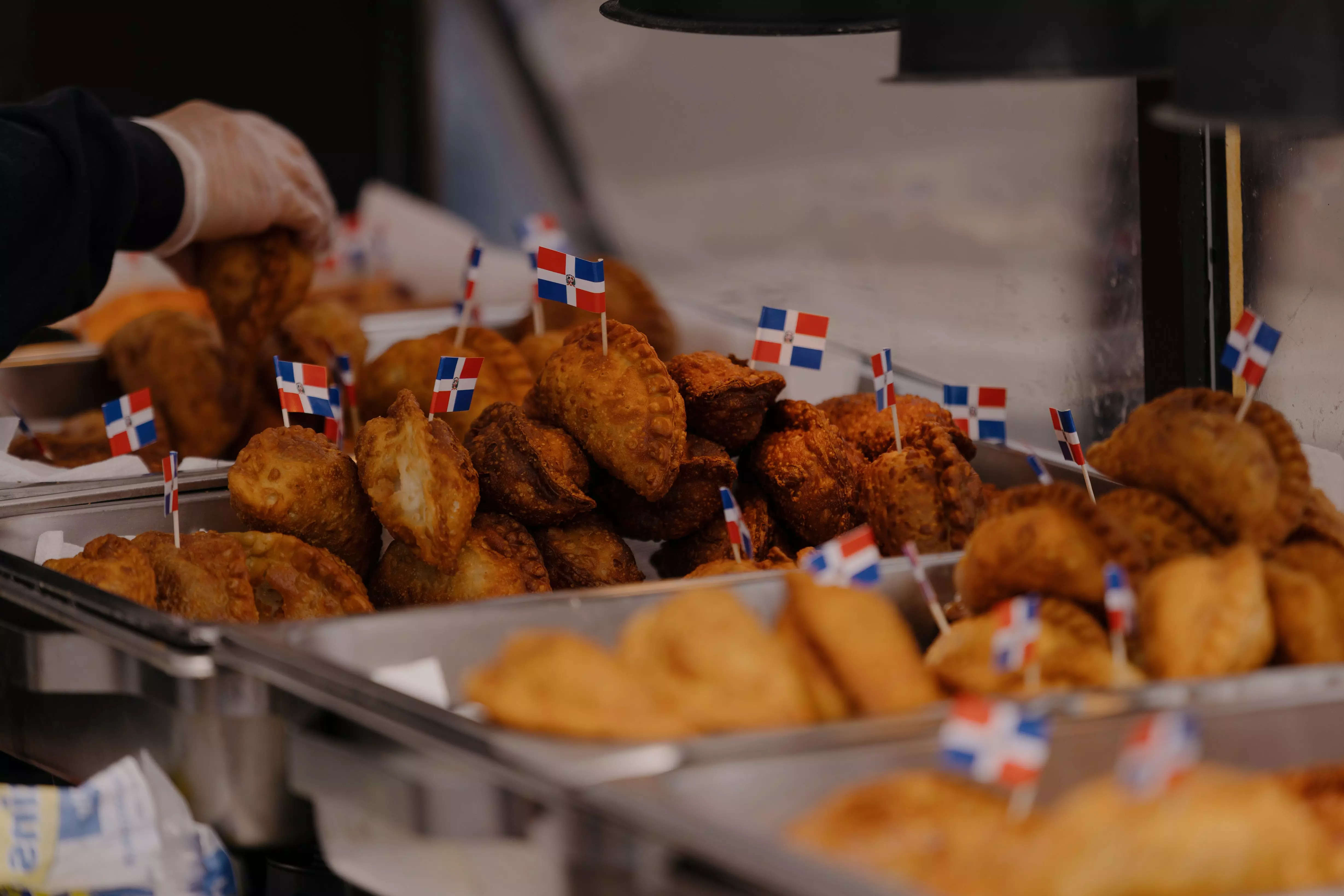Assortment of empanadas with Dominican flags on toothpicks on each one.