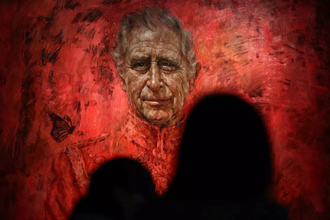 People out of focus looking at the portrait of King Charles III with a butterfly floating above his right shoulder.