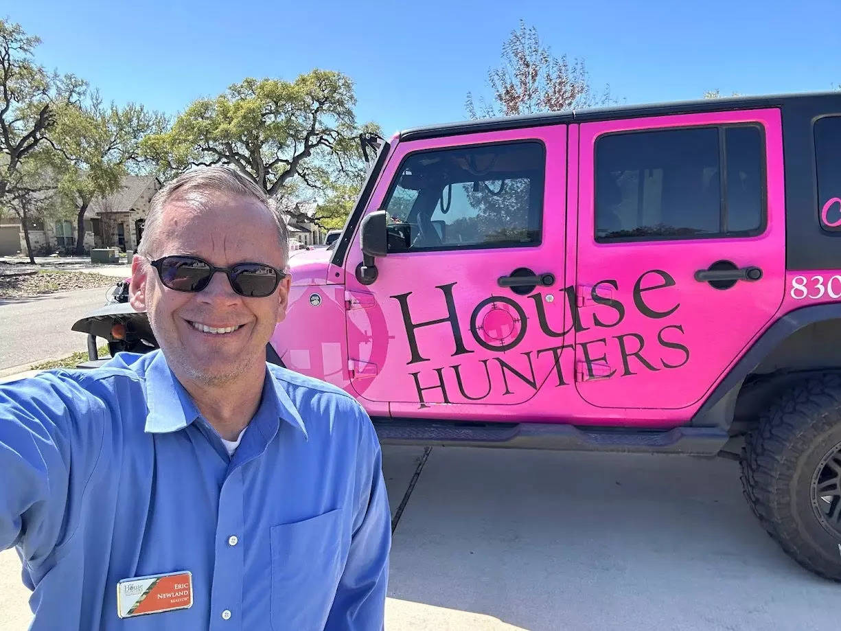 Eric Newland in front of a car with the House Hunters logo.