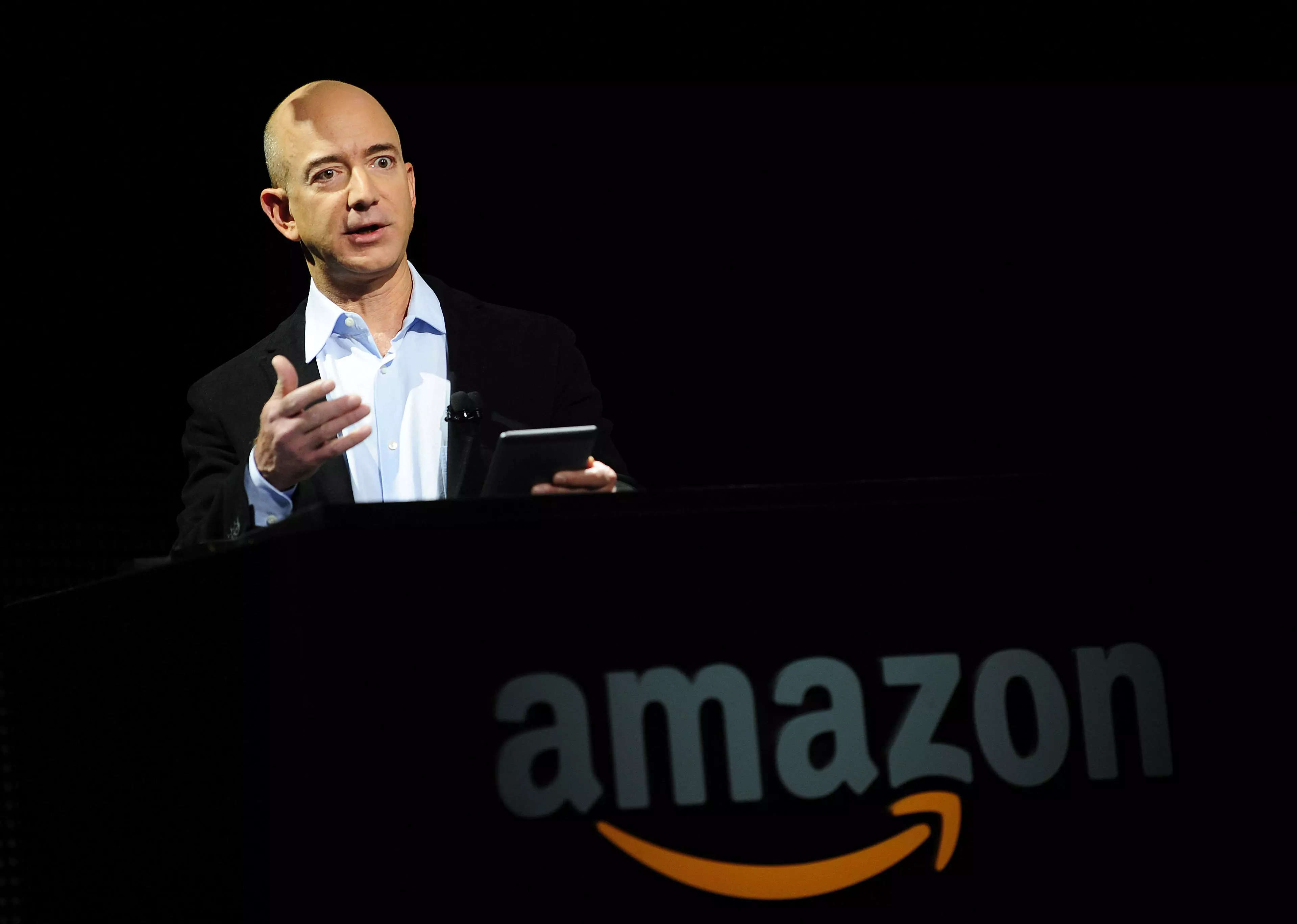 Jeff Bezos in a suit on top of an Amazon logo