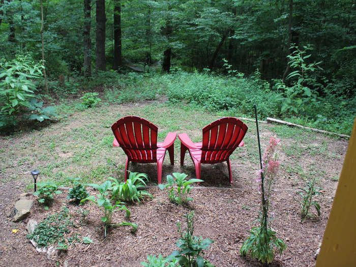 There were two red Adirondack chairs facing the woods and the nearby creek.