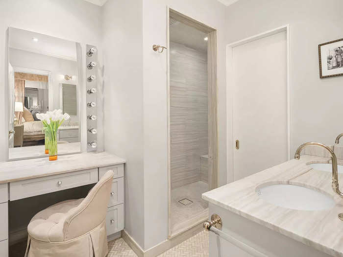 The connected bathroom has a shower, two sinks, and a vanity.