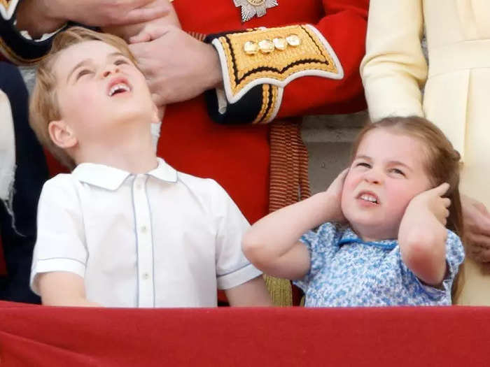 At the same event, George looked at the sky unhappily while Charlotte covered her ears.