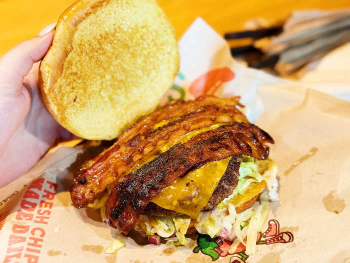 The Just Bacon Burger has one beef patty topped with bacon, cheddar cheese, pickles, lettuce, red onion, tomato, and mayonnaise. 