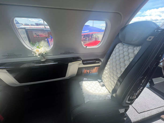 The four seats in the front have tables that pop out from the side, next to the vase of flowers.