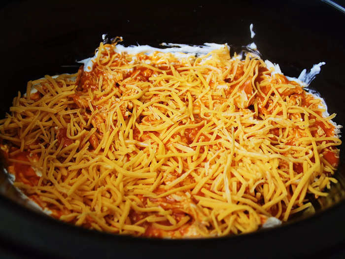 Next, I poured Buffalo wing sauce over the chicken-and-dip mixture and added a layer of shredded American cheese.