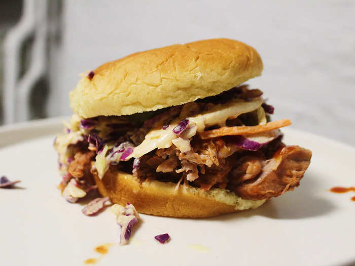 The recipe recommends serving the pulled pork in a sandwich with coleslaw and pickles.