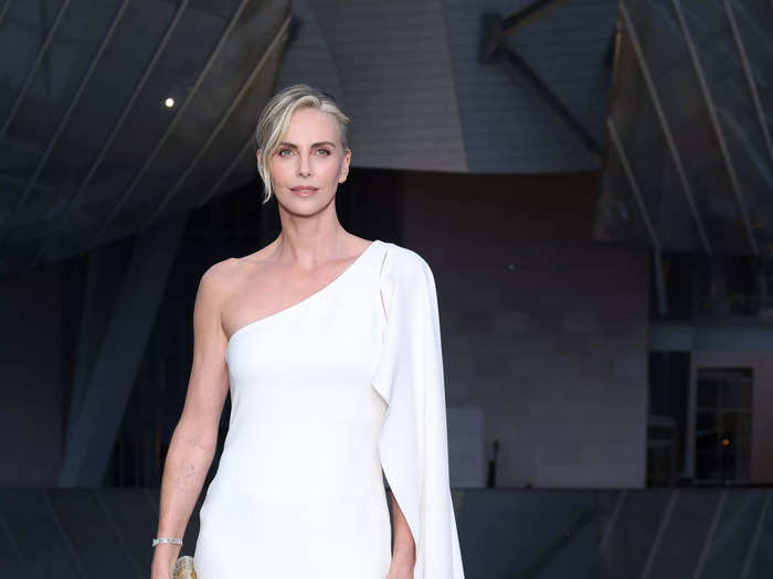 Charlize Theron looked elegant in a one-shoulder white minidress and gold clutch.