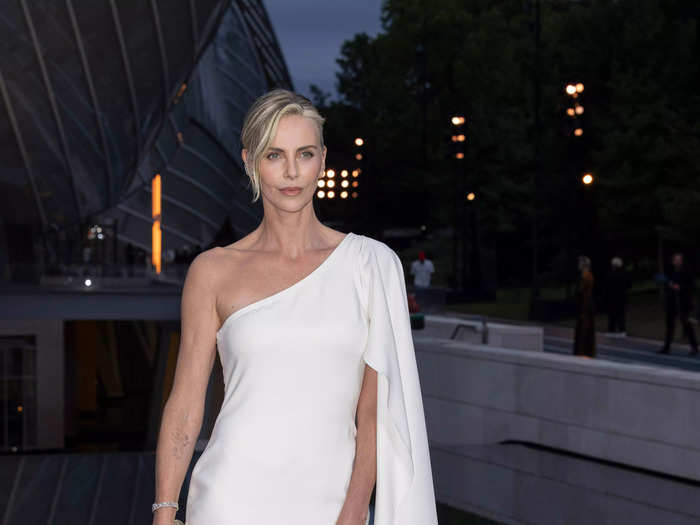 Charlize Theron also attended the pre-Olympics bash, wearing a white mini-dress featuring a flowing drape shoulder detail.