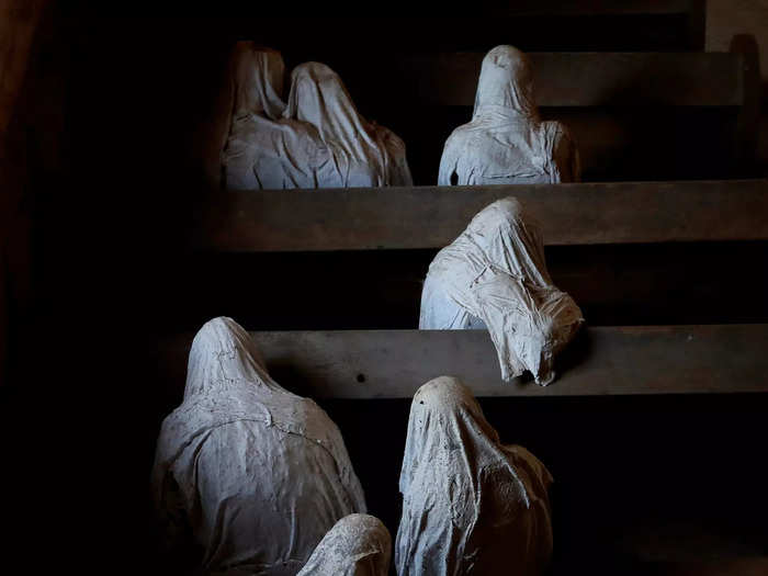 The eerie white figures sit solemnly in the pews.