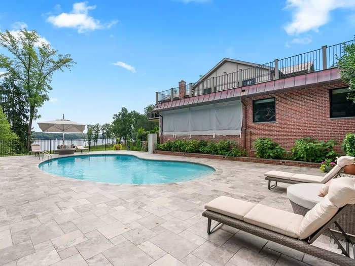 A stone patio surrounds the free-form heated gunite swimming pool.