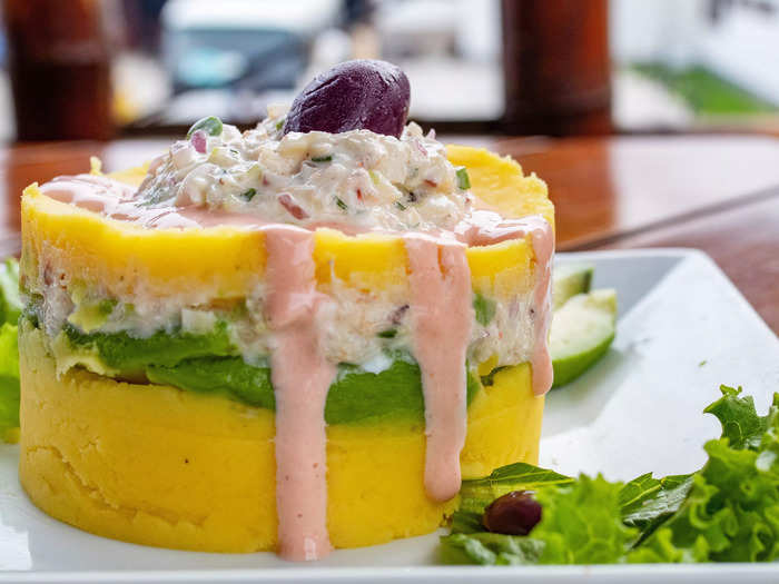 Peruvian causa rellena is stacked with chicken or tuna salad, aji, and mashed potatoes.