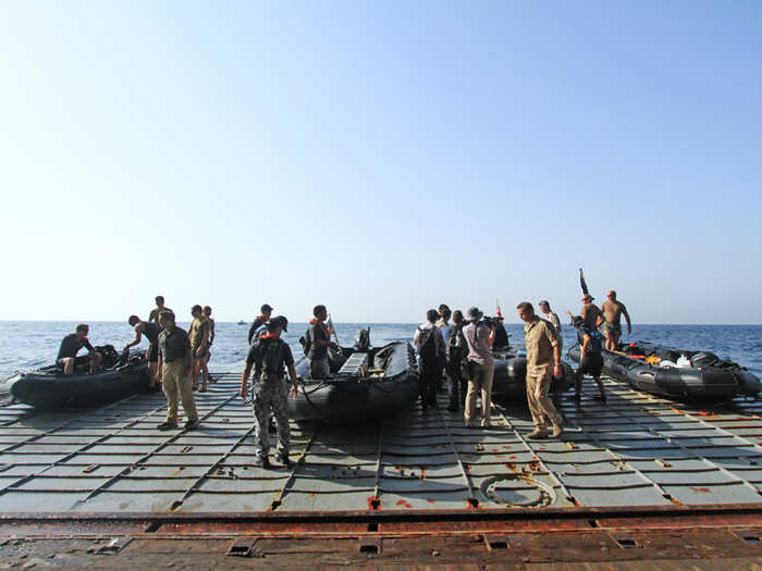 Allowing troops and equipment to get into and out of the water — here the divers have hauled their gear out over the slippery surface and are waiting for the ramp to drop them into the water