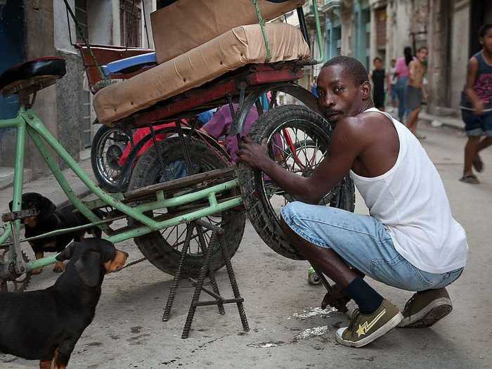 Rickshaws are also a common means of transportation. Here a man fixes the tire of a "Bicitaxi" while a couple of dachshunds keep him company.