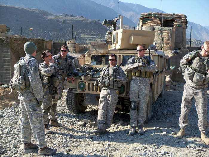 Soldiers of "Black Knight Troop". In the background, you can see mountains all around them, with a base perimeter of "Hesco" barriers and concertina wire.