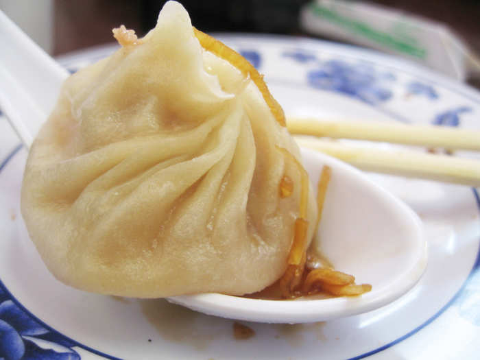 Learn how to properly eat soup dumplings in Shanghai: Use your chopsticks to pick up the top of the dumpling and dip it in soy sauce. Then place the dumpling on your soup spoon and poke a hole in it to let the soup drain out. Slurp up the soup and eat the dumpling.