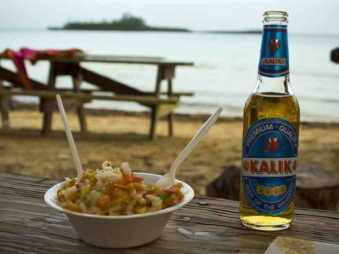 Cool off with a bowl of fresh Bahamian conch salad and a cold Kalik beer while listening to the waves and burying your feet in the sand in the Bahamas.