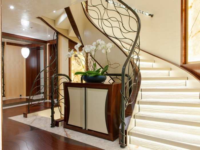 A grand staircase with a stylized modern banister beckons guests toward the upper levels of the ship.