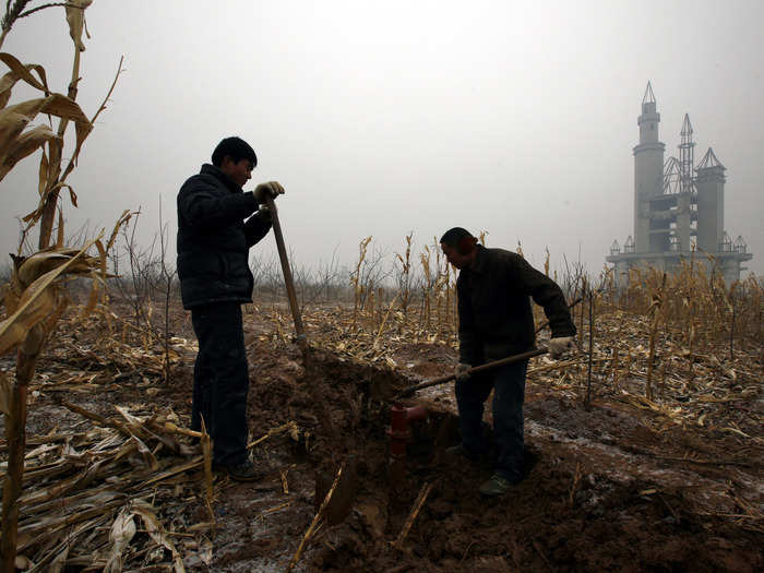 Farmers dig a water well in a field by the abandoned building.