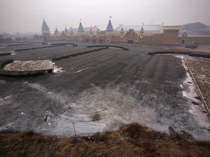 An unfinished parking lot is seen in front of the buildings.