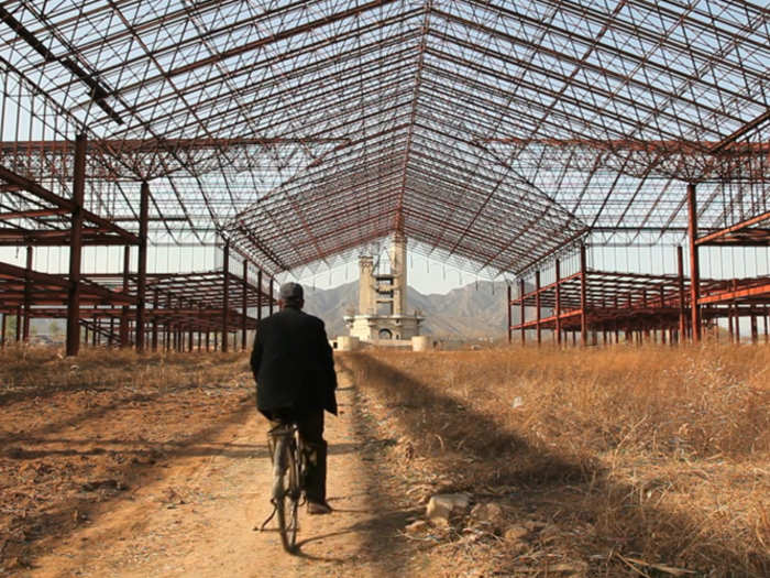 A biker rides past fields that locals now use for crops.