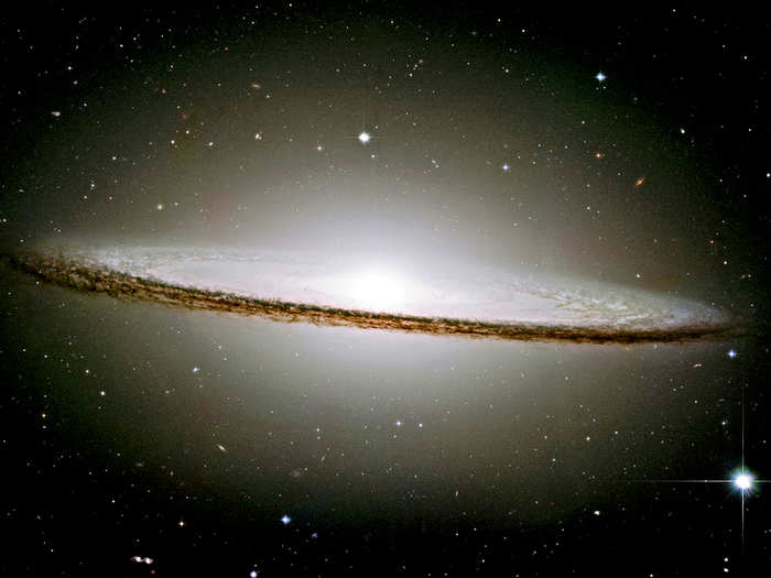 The "Sombrero Galaxy" is a spiral galaxy with a brilliant white core encircled by thick dust lanes.