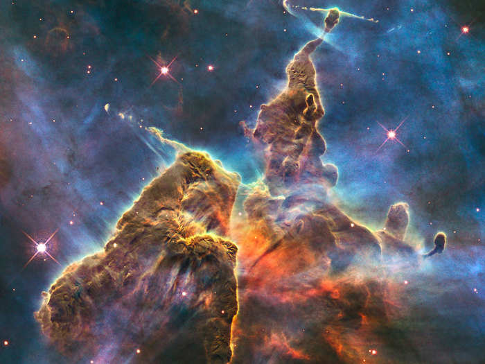 A view of “Mystic Mountain" captures a three-light-year tall pillar of gas being eaten away by the radiation of nearby bright stars.