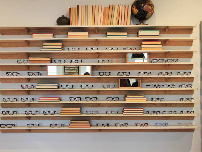 Glasses line all the walls with books and mirrors. These glasses are organized together because of their larger frames.