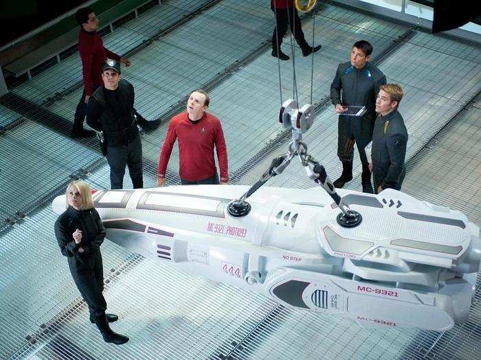 The crew appears to be looking over a model for a new ship.