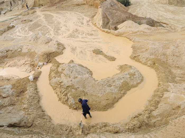 A laborer wades through water at a rare earth mine in Nancheng county, Jiangxi province.