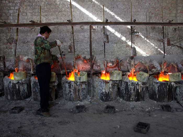 A worker stokes pots containing the rare earth metal Lanthanum.