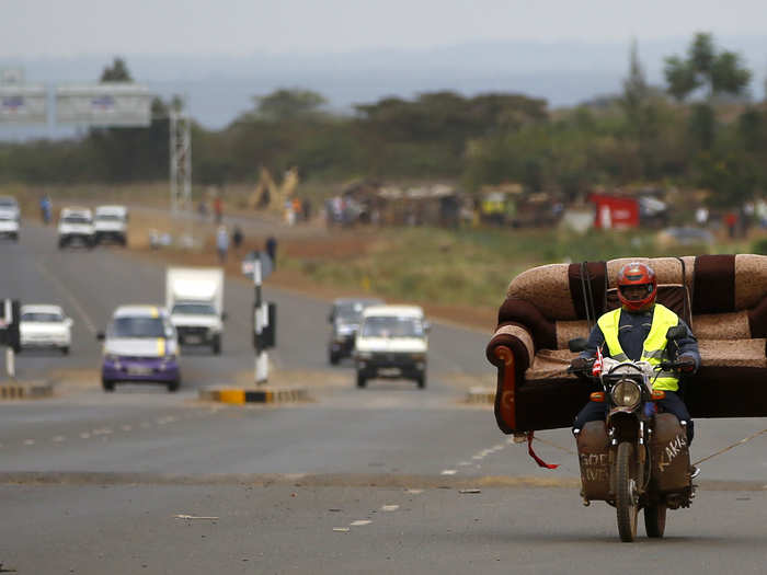 In Nairobi, Kenya, a man carries sofa on motorcycle.