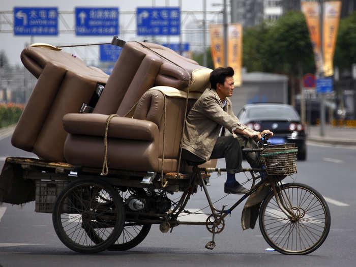 While in Beijing, a man bikes around with a lot of furniture.