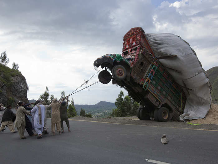 Pakistani men in Islamabad try to right a truck transporting wheat straw.