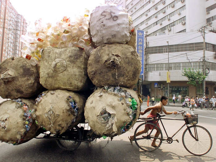 A Chinese man pushes a cart loaded with recyclable plastic containers.