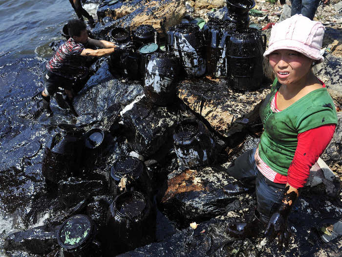 Fishermen clean up oil near a major northern Chinese port after a pipeline blast leaked more than 1,600 tons of heavy crude into the sea in July 2010.