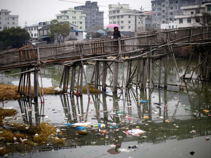 A woman walks on a bridge over a polluted river at a suburban area of Wenzhou, in Zhejiang province.