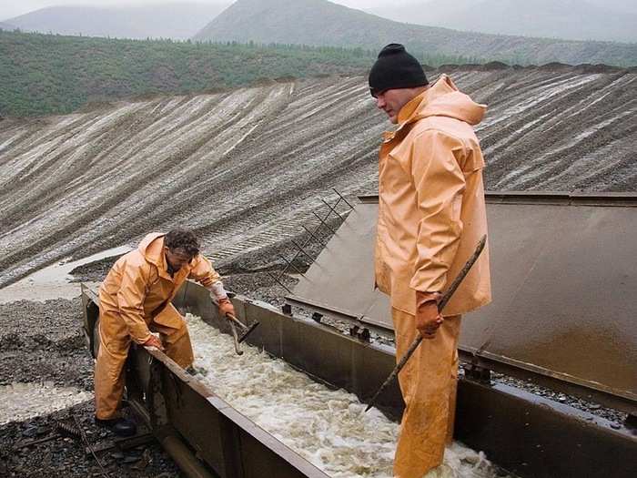 Workers open the lid of the pan (trough) and begin collecting the gold, by first flushing the mats of the trough.