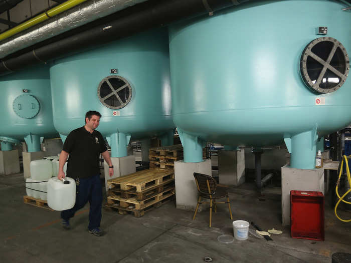 Another man walks past the huge water tanks that are used to filter water for the swimming pool.