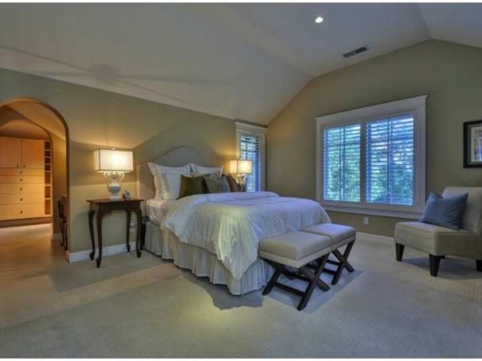 The master bedroom is spacious with vaulted ceiling and arched doorway.