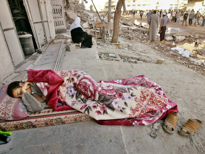 A Palestinian youth sleeps on the street as his house was destroyed at Zeitoun neighbourhood in Gaza May 13, 2004.